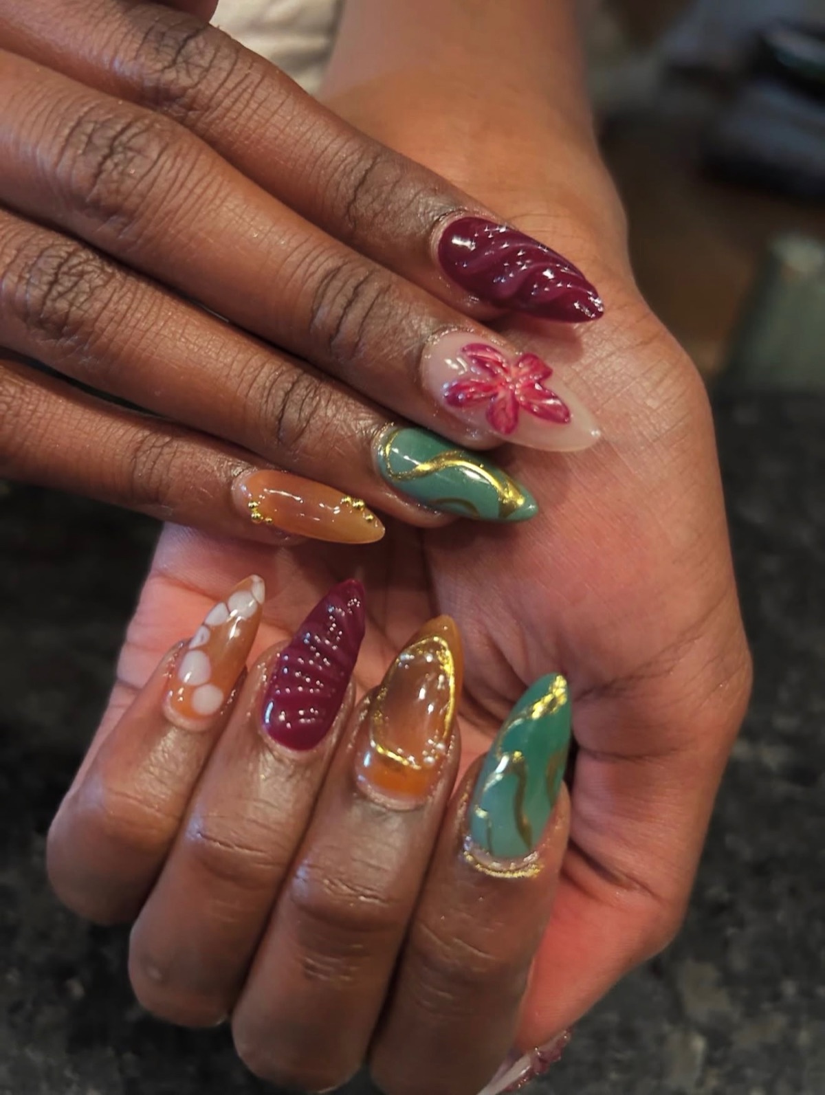 A finished custom set of colorful almond-shaped nail art by Amani Nails.